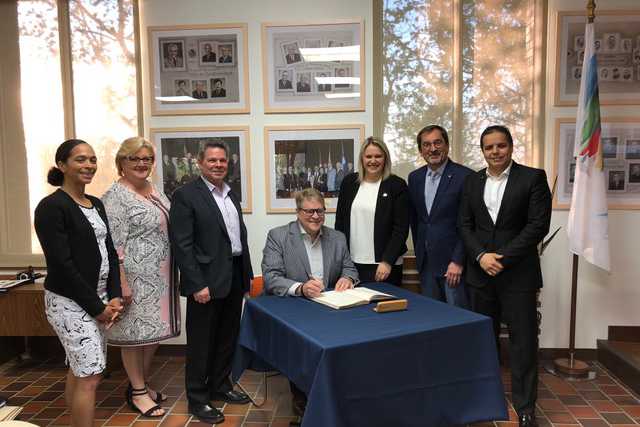 Martin Michaud, CEO of MDG (centre) signs the Visitors Book, with VP of finances, Jacques Foisy (left) and Mayor Christine Black (right) surrounded by the councillors of the Borough of Montreal-North