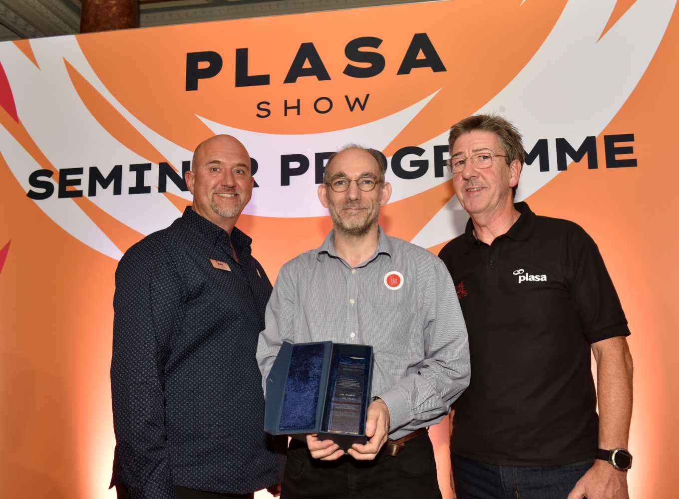 JB Toby (centre) receives his Gottelier Award trophy from PLASA chair, Adam Blaxill (left) and PLASA MD, Peter Heath (right)